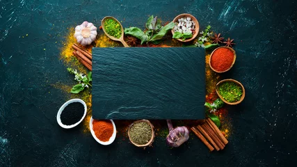 Keuken spatwand met foto Colorful herbs and spices for cooking. Indian spices. On a black stone background. Top view. © Yaruniv-Studio