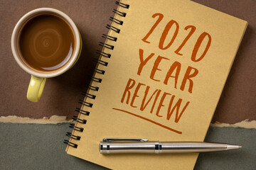 2020 year review text in a spiral notebook with a pen and coffee, business year summary and evaluation concept