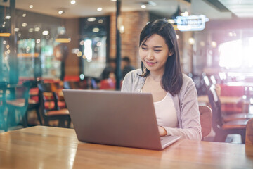 Young Asian woman using laptop computer and tablet PC to working in the modern co working space	