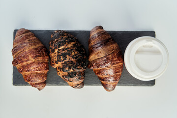 Red cup with coffee and a croissant on a table in a cafe. Morning breakfast. High-quality photo