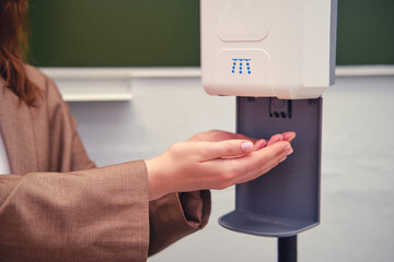 Teacher hands at the dispenser with antibacterial disinfection soap