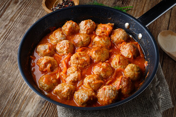 Meatballs in a pan in sweet and sour tomato sauce
