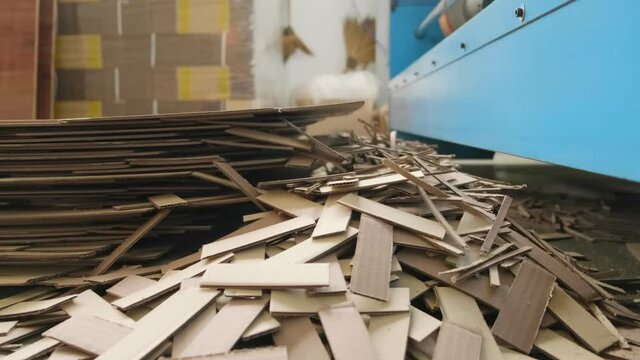 Dolly in scene of heavy industrial machine working on process of card board cutting and throwing on the floor with unused piece.