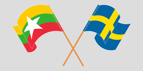 Crossed and waving flags of Myanmar and Sweden