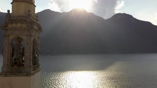 Epic Church Clock Tower Closeup with sun rays on a lake with mountains in the background, Nesso, Lago di Como, Italy