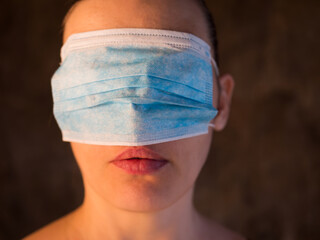 adult girl put on disposable medical mask on her eyes. Beautiful red lips. concept of social problems and lack of personal protective equipment. Coronavirus epidemic Italy, America, China, Spain