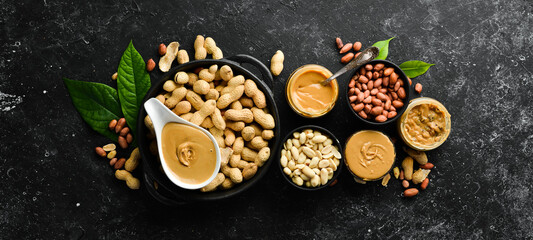 Peanut butter and nuts on a black stone background. Healthy food. Top view.