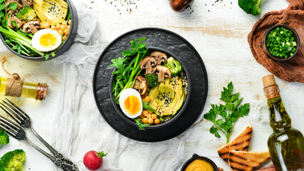 Buddha bowl: avocado, chickpeas, mushrooms, egg and arugula in a black bowl. Top view. Free space for text.
