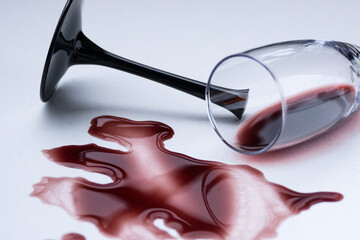Broken wine glass and spilled wine on a light background. Broken love, depression and hopelessness...