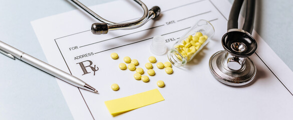 Medical concept. Yellow pills with stethoscope, pills, notepad, medical prescription, pen on the doctor's desktop. Treating a patient in a hospital with medication.