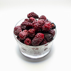 Zarzamoras  frescas y congeladas con fondo blanco en vaso de cristal