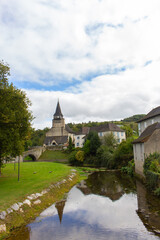 Obraz premium Landmark of medieval town in France. Ancient village on the river bank. Church with bridge over river in the mountains. Medieval heritage. Old architecture. Beautiful ancient village in Europe. 