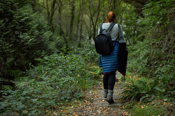 View from behind of a girl walking along a forest path.