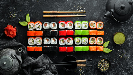 Sushi background. Assortment of Japanese food, sushi and tea on a black stone background. Top view. Free space for your text.