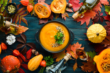 Pumpkin soup with pumpkin and colored autumn leaves. flat lay. On a blue wooden background. Top...