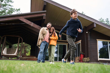 Joyful boy spending time with parents outside the house