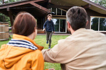 Fototapeta premium Cheerful adorable boy running to parents outdoors