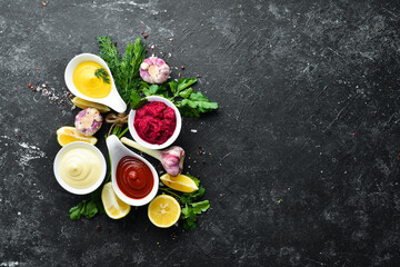 Set of sauces and spices on stone background. Sauces: mayonnaise, ketchup, tartare, barbecue and chili sauce in bowls.