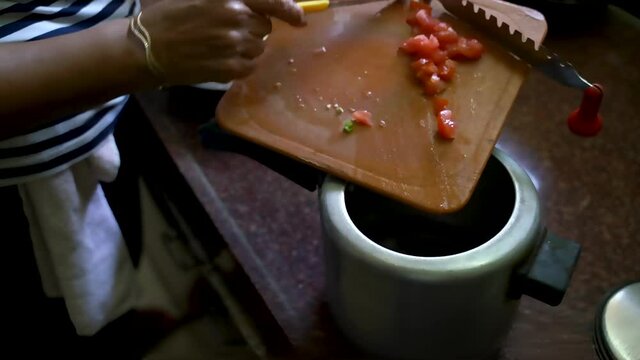 Putting Some Chopped Tomatoes On The Pot Of A Pressure Cooker. - Wide Shot  