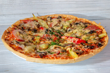 pizza with cheese vegetables and meat on a wooden background