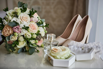 bridal accessories such as shoes, bouquet , ring and parfume on a table