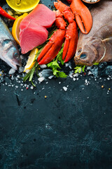 Fresh seafood and fish on black stone background. Flounder, lobster, squid, tuna, fish. Top view. Free copy space.
