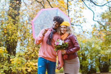 Man and woman of different ethnicity hugging in fall
