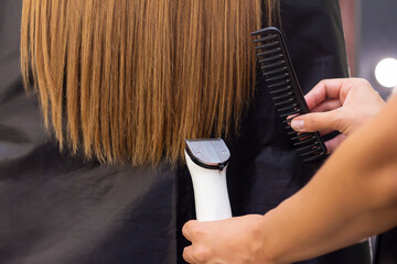 Naklejka premium Hairdresser with a hair machine. cutting off split ends of hair with a clipper. close up.