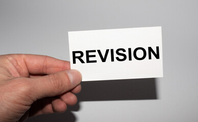 Message on the card REVISION, in hands of businessman.