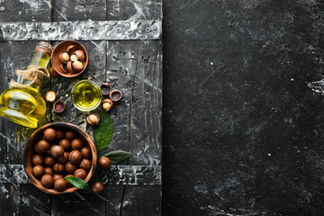 Macadamia nut in bowl on black stone background. Top view. Free space for your text.