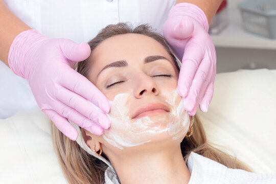 cosmetology. Close up picture of lovely young woman with closed eyes receiving facial cleansing procedure in beauty salon.