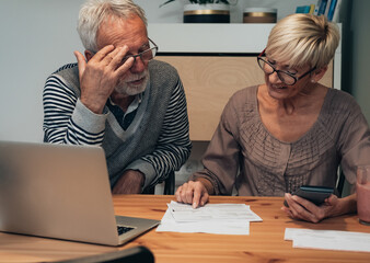Tensed mature couple discussing their monthly expenses at home stock photo