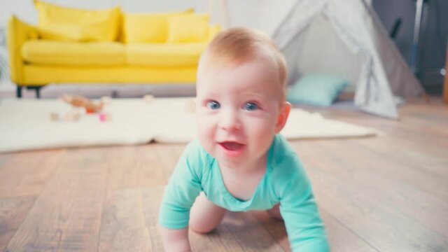 baby boy looking at camera while crawling at home
