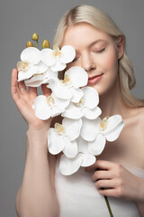 Obraz na płótnie Canvas Charming young woman holding beautiful white flower