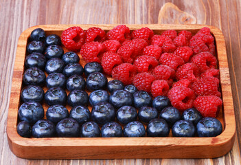 blueberries and raspberries on wooden plate