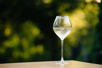 A glass of white wine outdoors at sunset. Exquisite white wine in a glass against the background of the garden