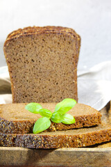 Sliced rye bread with leaf basil on cutting board. Whole grain rye bread with seeds