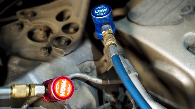 Refueling a car air conditioner in an old workshop. Footage. Auto repair with beautiful red and blue pressure pipes