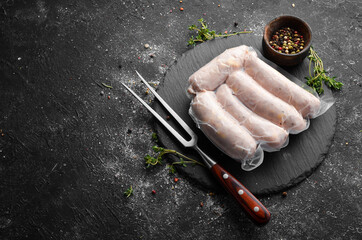 Raw chicken sausages with cheese in a vacuum package. Top view. On a black background.