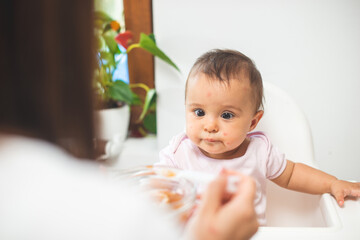 Mother feed her little daughter with a spoon