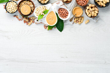 Fototapeta na wymiar Peanut butter and nuts on a white wooden background. Free space for your text.