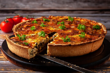 French quiche with chicken and mushrooms on wooden background