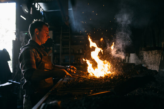 Blacksmith heating iron in fire