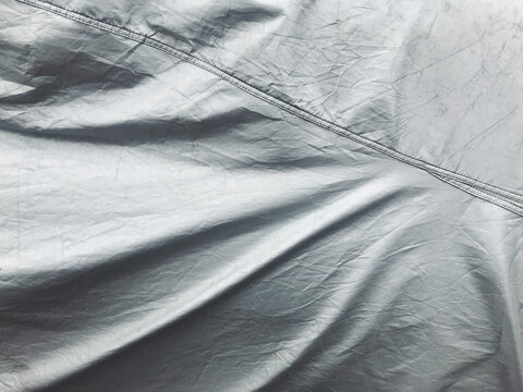 Metallic grey tarp covering sports car, close up