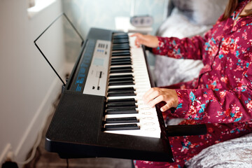 Girl in pajamas playing piano in a room