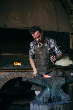 Blacksmith forging metal in workshop