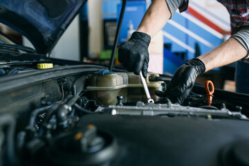 Crop man repairing car engine