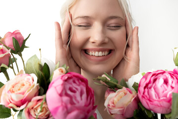 Cheerful young woman with flowers touching her face