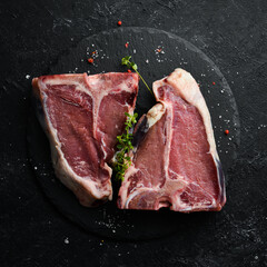Raw aged T-bone steak on a black stone background. Top view. Rustic style.