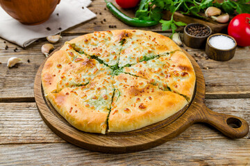 khachapuri with spinach on old wooden table, georgian kitchen